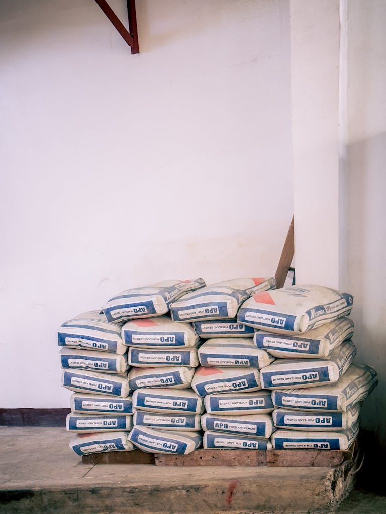A stack of bags of cement neatly arranged in an indoor warehouse environment.